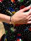 Close up model image of Venessa Arizaga FW26 Sweetheart Sparkle Bracelet (Black) - A layered bracelet with black threadwork, seed beads, gold plated chains, rhinestone chain, and a pave heart charm. 