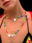Venessa Arizaga SS26 Rainbow Aura Necklace layered at collarbone with the Rainbow Heartbeat Adjustable Necklace worn as a choker, rainbow charms catching the light, perfect for a sun-drenched Paradisiac escape and effortless beach vibe.