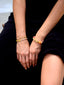 Close up of Venessa Arizaga SS26 Good Vibes Only Bracelet on wrist — adjustable black threadwork with multi-layer gold chains, glass pearls, and beaming smiley face charms; adjustable friendship bracelet design radiating handmade positivity, with rainbow and neon glass pearls Happy AF Elastic Bracelet, perfect for everyday wear.