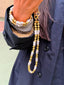 Model image of Venessa Arizaga FW26 Me Me Me Phone Leash - A statement gold beaded phone leash and bag charm with ceramic letter charms spelling "me", and Venessa Arizaga FW26 Talk of The Town Bracelet -  A statement three-row gold beaded elastic bracelet with ceramic letter charms spelling "xo", "luv", "me", "you", "hi", "bye", "yes", "no", "omg".