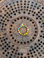 Colorful beaded Venessa Arizaga Glitter Galaxy bracelet on a rusted metal manhole cover