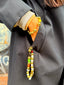 Model image of Venessa Arizaga FW26 Glitter Galaxy Bracelet - A golden beaded bracelet with classic icons - rainbow, smiley, butterfly, eyeball, mushroom, clover - perfect for everyday layering and Venessa Arizaga FW26 Glitter Galaxy Phone Leash - A golden beaded phone strap/bag charm with ceramic and wooden charms in star, clover, bear, ladybug, butterfly, and flowers, perfect for making an everyday statement