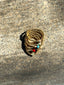 Lifestyle image of Venessa Arizaga FW26 Dreamwave Bracelet - Five rows of elastic gold beads and charms including a smiley face, ladybug, mushroom, alien, and star. Gold beaded bracelet with charms on a gray surface.
