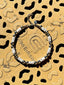 Lifestyle image of Venessa Arizaga FW26 Me Me Me Necklace (Silver) - A statement silver beaded necklace with ceramic letter charms spelling "me" on a textured gold surface.