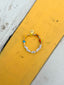 Venessa Arizaga FW26 High On Life Bracelet - A golden beaded bracelet with classic icons - smiley, flower, mushroom, hot air balloon, and butterfly - perfect for everyday layering. Bracelet with colorful beads and letter beads on a yellow and gray surface.