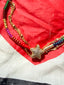 Lifestyle image of Venessa Arizaga FW26 Twinkle Bracelet - An everyday adjustable multi-layer bracelet with brown threadwork, rainbow seed beads, gold-plated chains, and a pavé star charm. Multicolored beaded bracelet with a gold charm on a red heart-shaped fabric.
