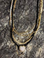 Lifestyle image of Venessa Arizaga FW26 Sweetheart Sparkle Necklace (Black) - A statement layered necklace with black threadwork, seed beads, gold plated chains, rhinestone chain, and a pave heart charm. Multi-layered necklace with heart pendant on a textured stone surface