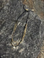 Lifestyle image of Venessa Arizaga FW26 Sweetheart Sparkle Necklace (Black) - A statement layered necklace with black threadwork, seed beads, gold plated chains, rhinestone chain, and a pave heart charm. Multi-layered necklace with heart pendant on a textured stone surface