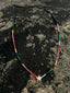 Lifestyle image of Venessa Arizaga FW26 Twinkle Necklace - An everyday adjustable necklace with brown threadwork, rainbow seed beads, and a pavé star charm on a textured surface