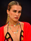 Venessa Arizaga SS26 Rainbow Aura Necklace layered at collarbone with the Rainbow Heartbeat Adjustable Necklace worn as a choker, rainbow charms catching the light, styled with Peace Out Sparkle Earrings and Shimmer Huggie Hoops Pave earring with mushroom, for sun-drenched Paradisiac escape and effortless surf-resort vibe.
