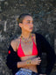 Model image of Venessa Arizaga FW26 Dreamwave Necklace - Two rows of gold beads and playful charms including a smiley face, ladybug, mushroom, alien, and star and the Dreamwave Bracelet - Five rows of elastic gold beads and charms including a smiley face, ladybug, mushroom, alien, and star . Model in colorful outfit standing against a textured wall.