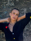 Close-up model image of Venessa Arizaga FW26 Lover Necklace - An everyday adjustable necklace with black threadwork, black glass seed beads, and sparkling rhinestone heart charms. Model wearing a black cardigan with a textured wall background