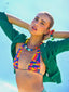 Close up model image of Venessa Arizaga FW26 Over The Rainbow Necklace & Bracelet - A colorful beaded statement necklace and bracelet with rainbow gradient charms including heart, flower, smiley, clover, eyeball, mushroom, butterfly, bead, and ladybug in ceramic, wood, and glass.