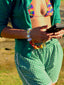 Close up model image of Venessa Arizaga FW26 Over The Rainbow Phone Leash- A colorful beaded statement multi use phone accessory and bag charm with iconic charms in rainbow hues including heart, flower, smiley, clover, eyeball, mushroom, butterfly, bead, and ladybug in ceramic, wood, and glass.