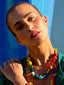 Close up model image of Venessa Arizaga FW26 Over The Rainbow Necklace & Bracelet - A colorful beaded statement necklace and bracelet with rainbow gradient charms including heart, flower, smiley, clover, eyeball, mushroom, butterfly, bead, and ladybug in ceramic, wood, and glass.