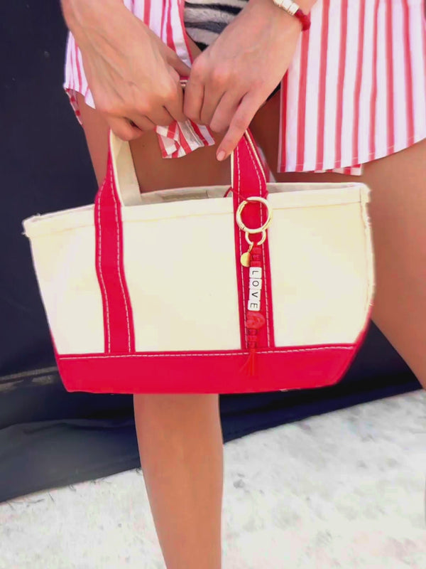 Close up of Venessa Arizaga SS26 Sugar Rush Love Bag/Key Charm attached to tote, love heart motif bringing together a playful look. Perfect for valentine's day and every day.